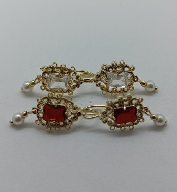 Aretes Tlalmanalli Aretes Tlalmanalli. Laminado de oro, gema rectangular (roja/transparente) con filigrana y perlas.