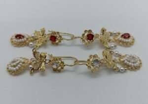 Aretes Tlaliltik Tlamachtli Aretes Tlaliltik Tlamachtli. Laminado de oro, diseño colgante con mariposa, perlas y gema en filigrana.