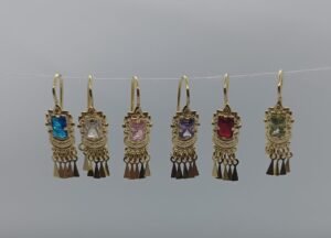 Aretes Milagrito de Color Aretes Milagrito de Color. Laminado de oro, gema cuadrada de colores y flecos colgantes.