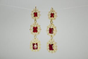 Aretes Candelabro Escarlata. Laminado de oro, diseño largo de filigrana con 3 gemas rojas rectangulares.