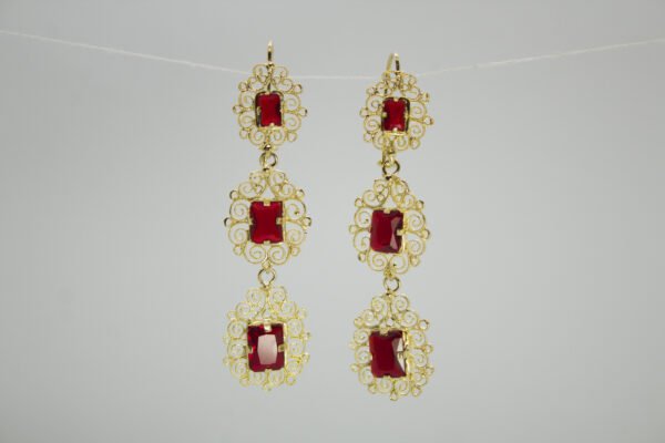 Aretes Candelabro Escarlata Aretes Candelabro Escarlata. Laminado de oro, diseño largo de filigrana con 3 gemas rojas rectangulares.