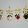 Aretes Nudo de Gala Aretes Nudo de Gala. Laminado de oro, moño brillante y gema ovalada de color (rosa, transparente, rojo, negro).