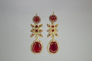 Aretes Flor de Nochebuena. Laminado de oro, diseño largo con flores y gema de lágrima roja.