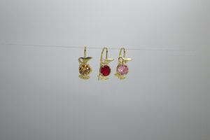 Aretes Jarrito Mágico Aretes Jarrito Mágico. Laminado de oro, diseño de jarra con gema de color (rojo, rosa, ámbar).